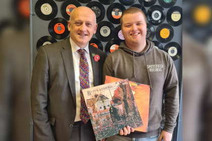 Vinyl music shop owner in front of decorative vinyl's on the wall