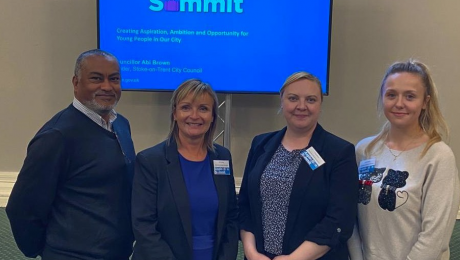 A team of colleagues pictured smiling in front of a screen