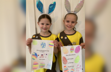 Two young girls showing their posters wearing their brownies uniform