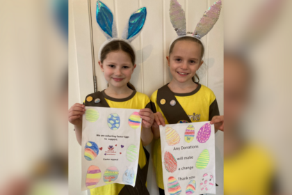 Two young girls showing their posters wearing their brownies uniform