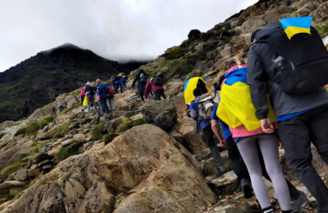 A group of people climbing up a hill with a lot of rocks and steps on the way to the top.
