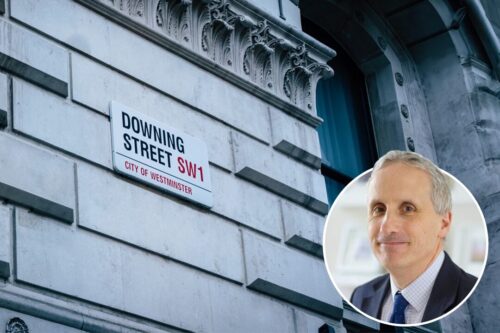 Staffordshire Chambers of Commerce's Declan Riddells headshot in a circle at the bottom right of a picture of Downing Streets road sign on the wall.