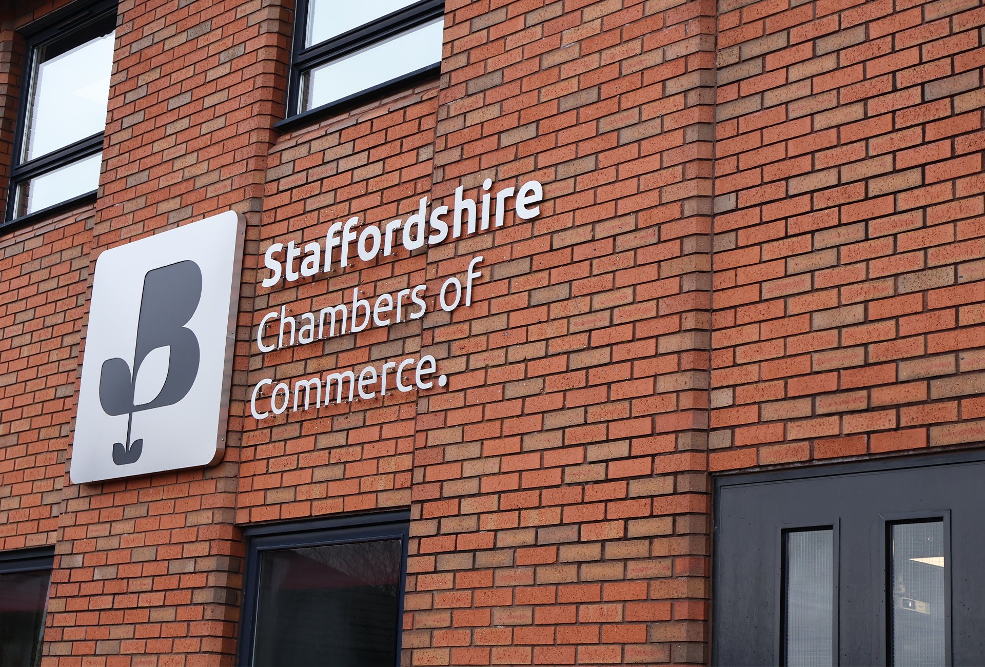 Exterior view of the Staffordshire Chambers of Commerce building, showing a large logo and signage mounted on a red brick wall.