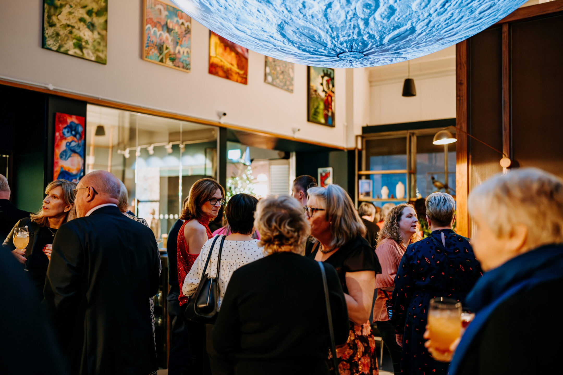 Attendees networking at a Staffordshire Chambers event held at Lunar at Wedgwood, under a striking illuminated moon installation in a venue with colourful artwork on the walls.