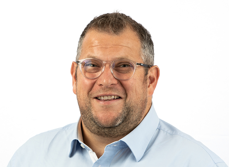 Portrait of Steve Timmis, wearing glasses and a light blue shirt, smiling at the camera.